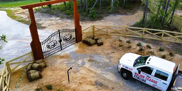 Estate decorative steel gate at a ranch with a crossbuck wood fence