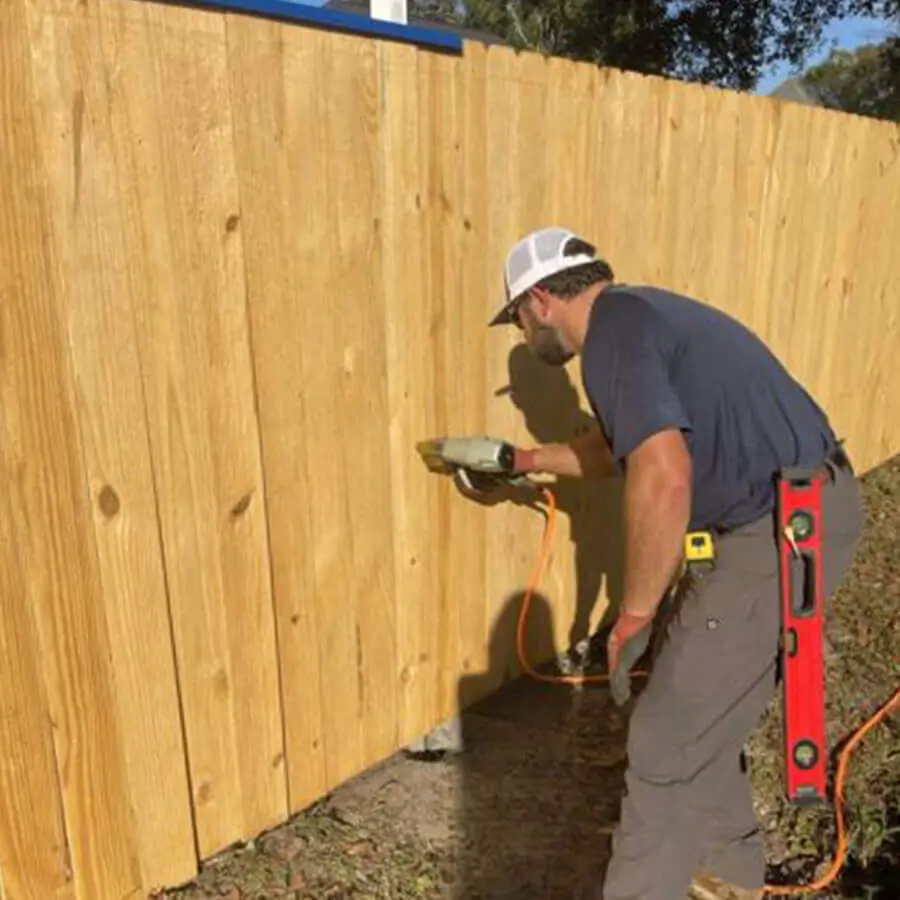 Man installing picket into a wood privacy fence